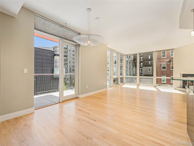 unfurnished living room featuring floor to ceiling windows, light hardwood / wood-style flooring, and a notable chandelier