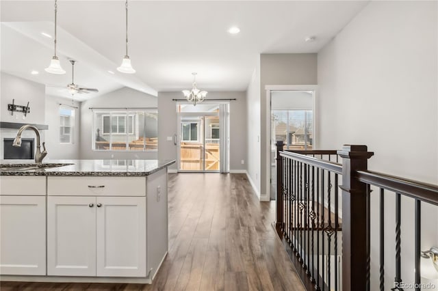 kitchen featuring sink, hanging light fixtures, dark stone countertops, dark hardwood / wood-style flooring, and white cabinets