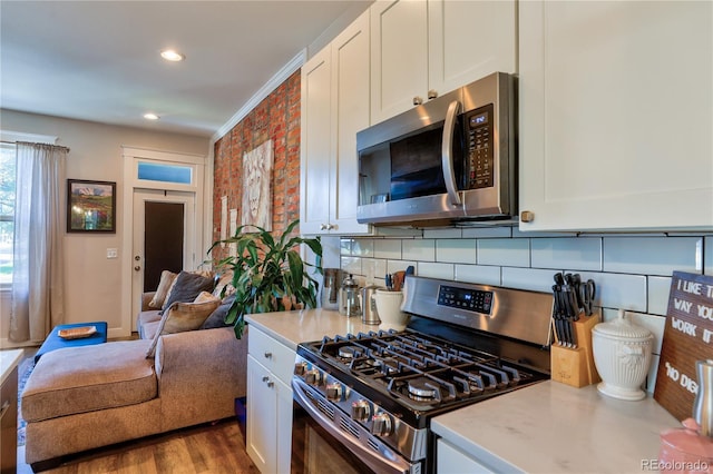1739 E Martin Luther King Jr Blvd, Denver, CO 80205 - kitchen with stainless steel appliances, white cabinetry, tasteful backsplash, recessed lighting, and wood finished floors