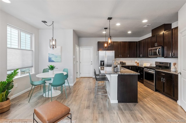 kitchen featuring light hardwood / wood-style flooring, appliances with stainless steel finishes, a healthy amount of sunlight, and a kitchen island with sink