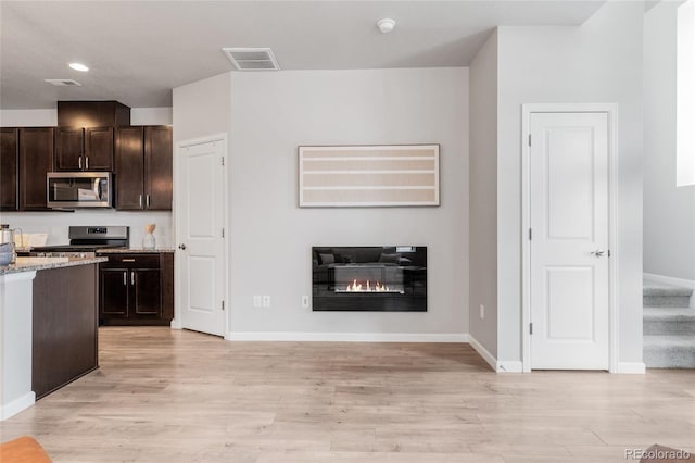 kitchen with dark brown cabinets, stainless steel appliances, light hardwood / wood-style floors, and light stone countertops