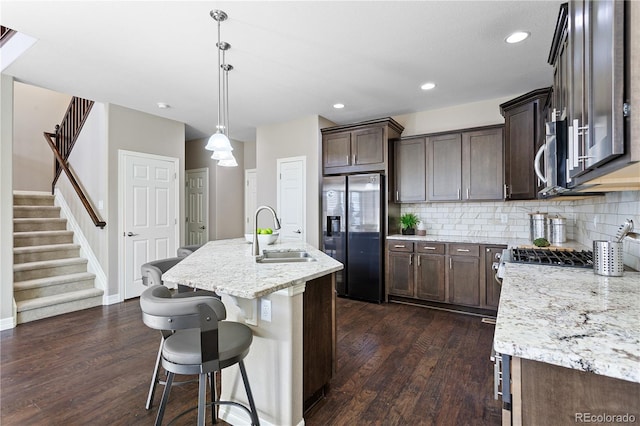 kitchen with pendant lighting, sink, a kitchen island with sink, backsplash, and stainless steel appliances