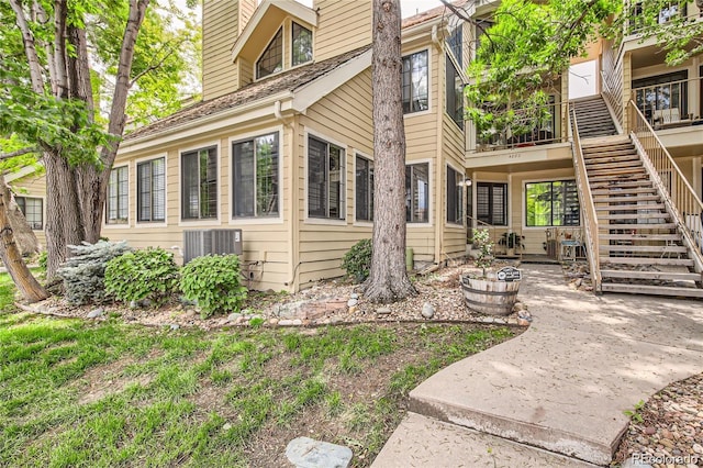 view of property exterior featuring central air condition unit, stairway, and a patio