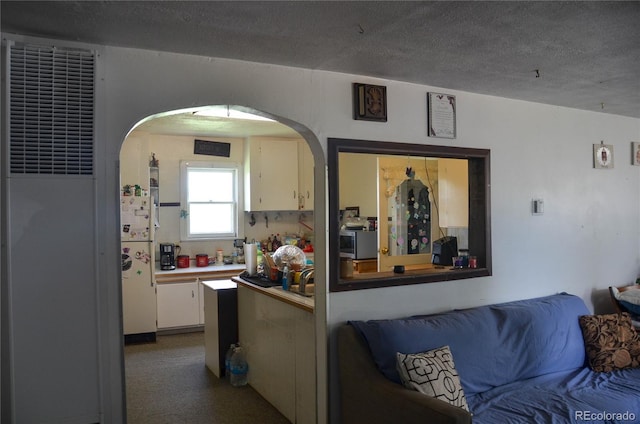 21064 Kelly St, Matheson, CO 80830 - kitchen featuring a heating unit, arched walkways, white cabinets, freestanding refrigerator, and a textured ceiling
