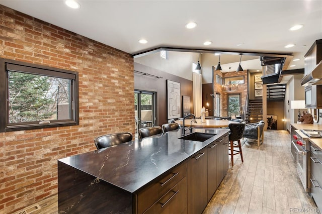 114 El Paso Blvd, Manitou Springs, CO 80829 - kitchen featuring modern cabinets, brick wall, light wood finished floors, a spacious island, and recessed lighting