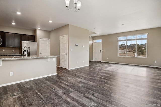 kitchen featuring dark hardwood / wood-style flooring, stainless steel fridge with ice dispenser, light stone countertops, dark brown cabinets, and an inviting chandelier