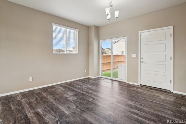 empty room featuring dark hardwood / wood-style floors and an inviting chandelier