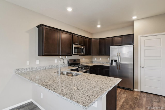 kitchen featuring appliances with stainless steel finishes, sink, light stone counters, and dark brown cabinetry