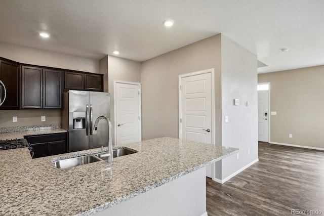 kitchen featuring sink, dark brown cabinetry, light stone counters, stainless steel refrigerator with ice dispenser, and dark wood-type flooring