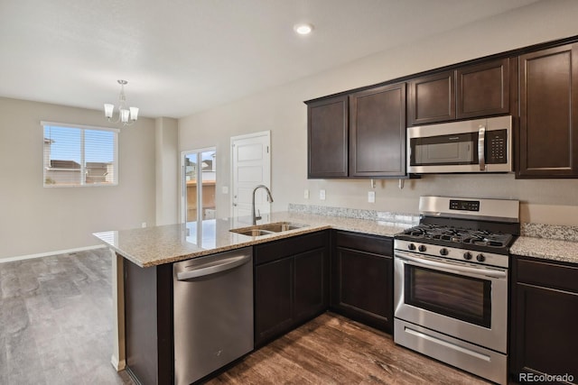 kitchen featuring appliances with stainless steel finishes, sink, hanging light fixtures, dark brown cabinetry, and kitchen peninsula