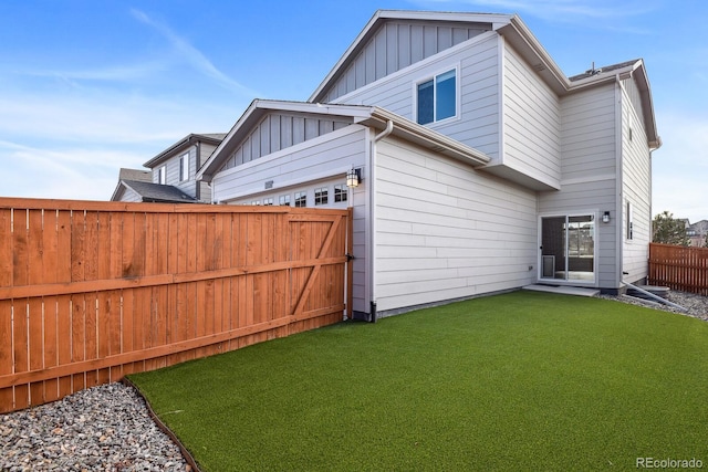 rear view of property featuring a garage and a lawn