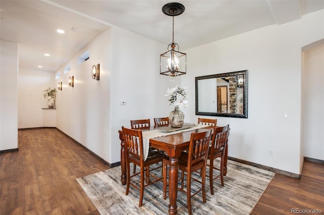 dining room with dark wood-type flooring and an inviting chandelier