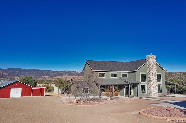 view of front of house featuring an outdoor structure, an outbuilding, a mountain view, and dirt driveway