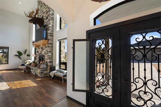 foyer featuring french doors, a healthy amount of sunlight, a towering ceiling, and wood finished floors