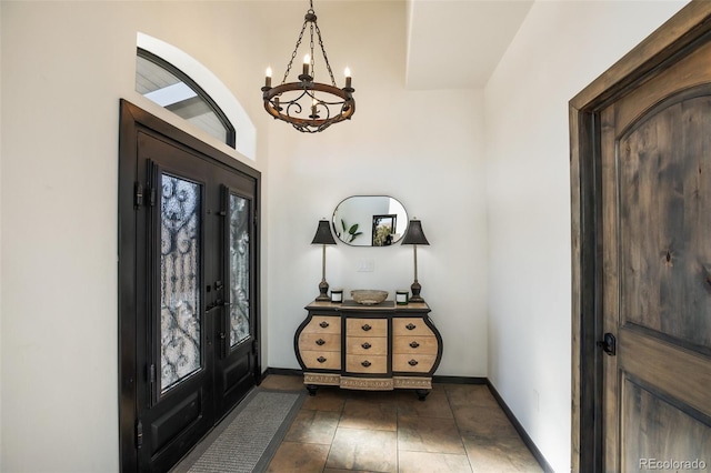 foyer with baseboards and a notable chandelier