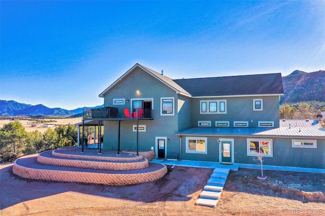 rear view of house with a mountain view and stucco siding