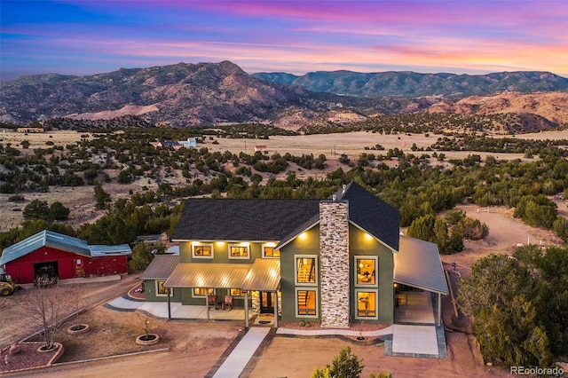 view of front of home featuring metal roof, stone siding, a mountain view, and stucco siding