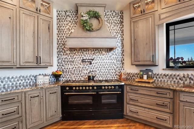 kitchen featuring stone counters, backsplash, double oven range, dark wood finished floors, and glass insert cabinets