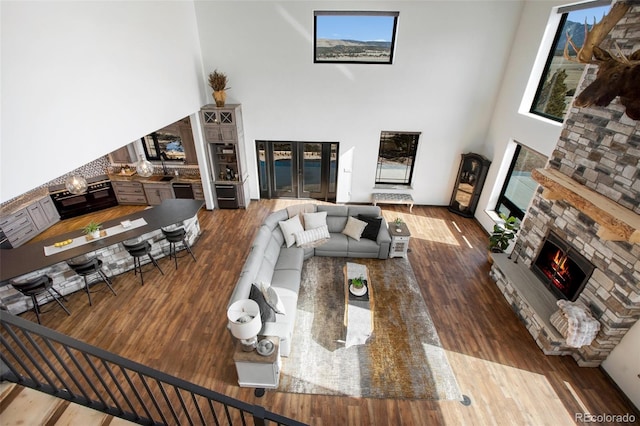 living area with a lit fireplace, a high ceiling, and wood finished floors