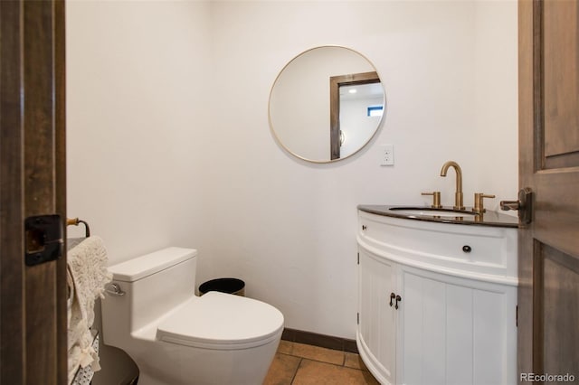 half bathroom featuring toilet, baseboards, vanity, and tile patterned floors