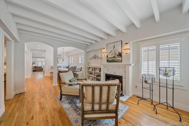 2340 S Columbine St, Denver, CO 80210 - living area with arched walkways, beam ceiling, light wood-style floors, a fireplace, and a chandelier