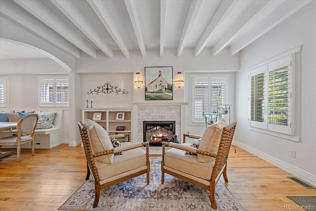 2340 S Columbine St, Denver, CO 80210 - living room featuring beam ceiling, wood-type flooring, a brick fireplace, and arched walkways