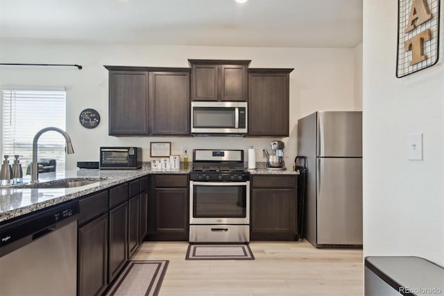 kitchen featuring light hardwood / wood-style floors, dark brown cabinets, sink, light stone counters, and appliances with stainless steel finishes