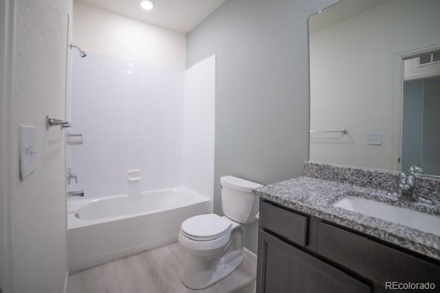 full bathroom featuring vanity, washtub / shower combination, toilet, and wood-type flooring