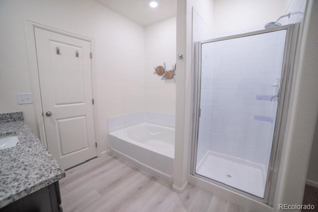 bathroom featuring hardwood / wood-style floors, vanity, and plus walk in shower