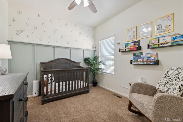 bedroom featuring ceiling fan, a nursery area, and carpet