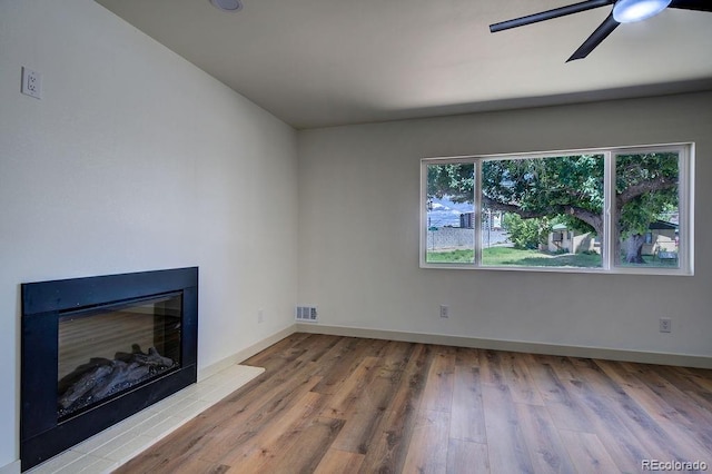 1815 S Monroe St, Denver, CO 80210 - unfurnished living room with wood finished floors, a ceiling fan, and a glass covered fireplace