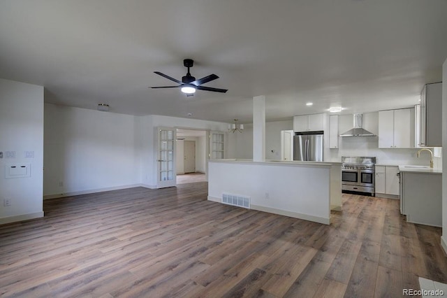 1815 S Monroe St, Denver, CO 80210 - kitchen featuring stainless steel appliances, wall chimney exhaust hood, open floor plan, wood finished floors, and recessed lighting