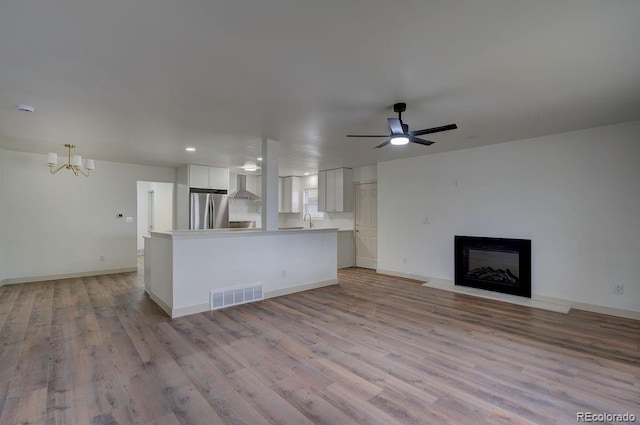 1815 S Monroe St, Denver, CO 80210 - unfurnished living room with light wood-style floors, a chandelier, a glass covered fireplace, a ceiling fan, and recessed lighting