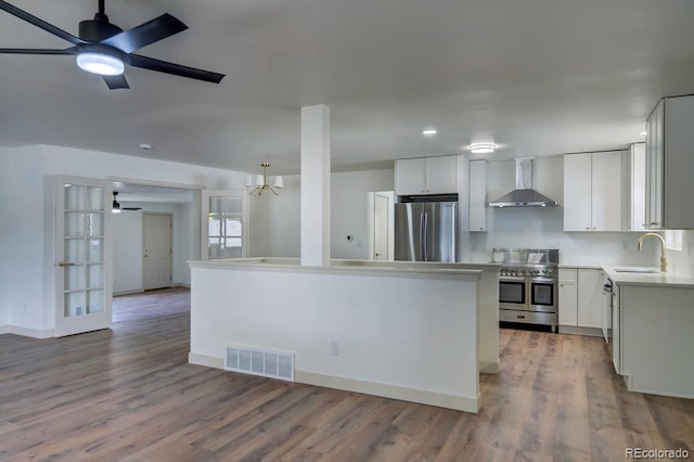 1815 S Monroe St, Denver, CO 80210 - kitchen with stainless steel appliances, wall chimney range hood, a ceiling fan, wood finished floors, and recessed lighting