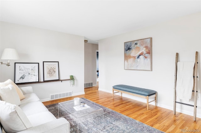 living room with wood finished floors, visible vents, and baseboards