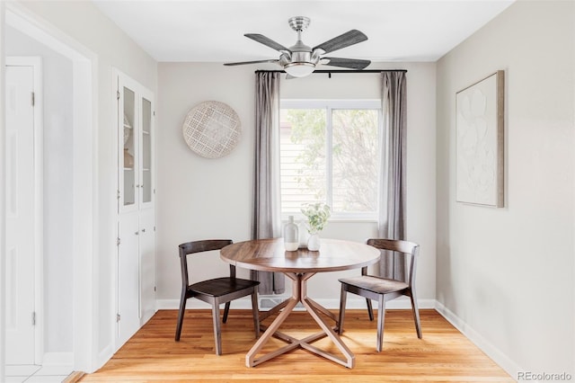 dining area featuring baseboards, a ceiling fan, and light wood-style flooring