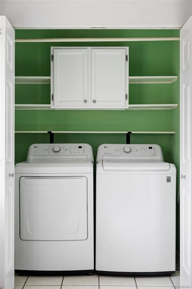 washroom featuring separate washer and dryer, cabinet space, and light tile patterned floors