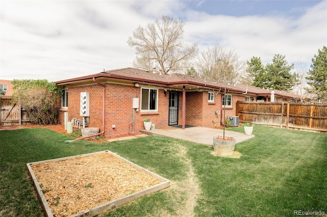 rear view of property featuring a lawn, a fenced backyard, brick siding, and a patio
