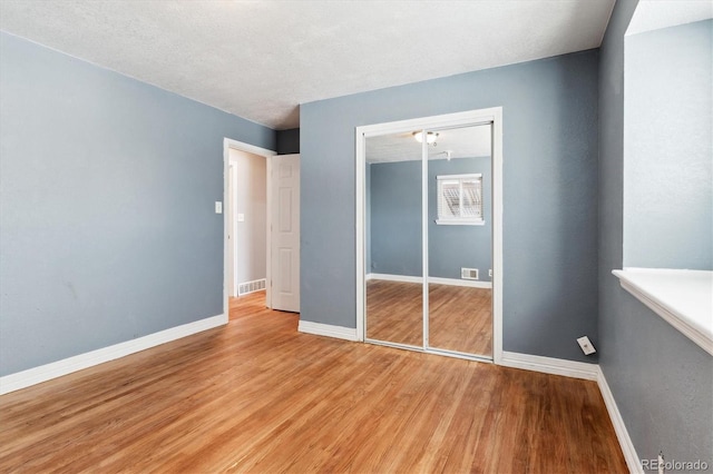 unfurnished bedroom with light hardwood / wood-style floors, a closet, and a textured ceiling