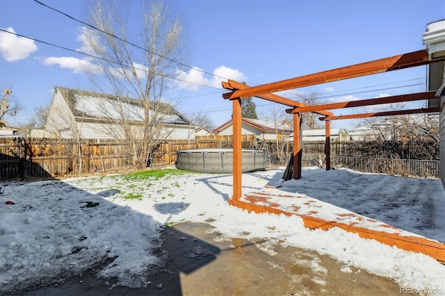 yard covered in snow with a pergola and a fenced in pool