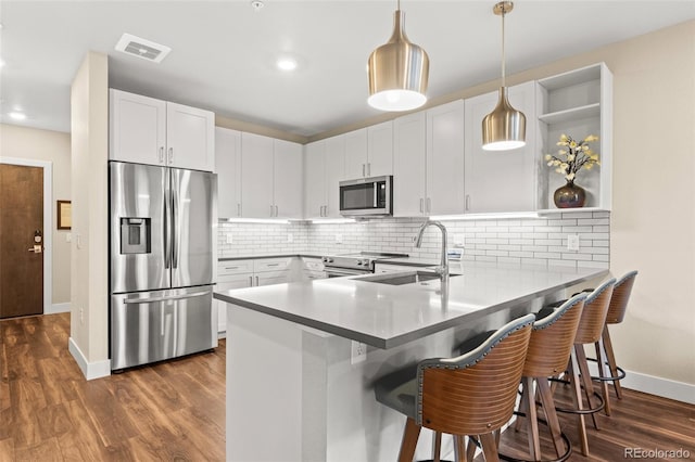 kitchen featuring a peninsula, baseboards, white cabinets, a sink, and stainless steel appliances