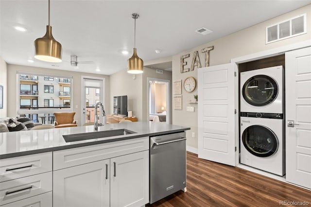 kitchen featuring visible vents, stacked washing maching and dryer, dark wood-type flooring, a sink, and dishwasher