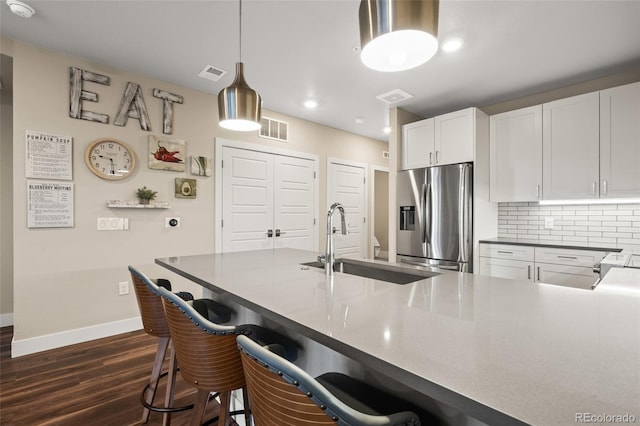 kitchen with a sink, stainless steel fridge with ice dispenser, dark wood finished floors, and visible vents