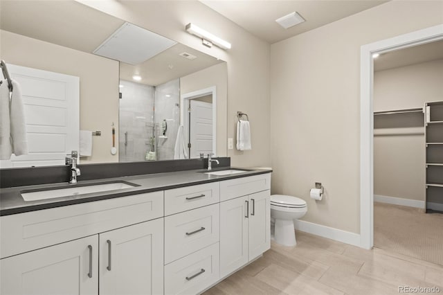 bathroom featuring toilet, baseboards, a sink, and a stall shower