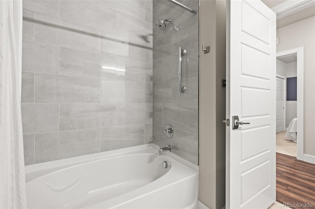 bathroom with washtub / shower combination and wood finished floors