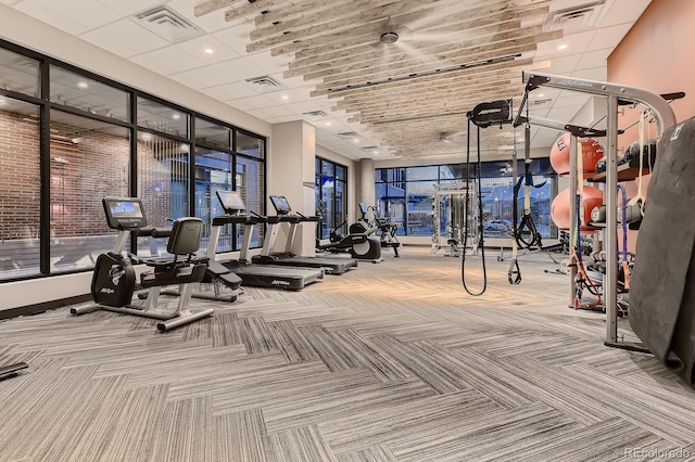 exercise room featuring carpet flooring, visible vents, and a towering ceiling