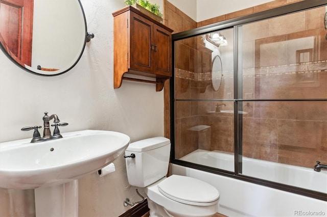 full bathroom with enclosed tub / shower combo, toilet, and sink