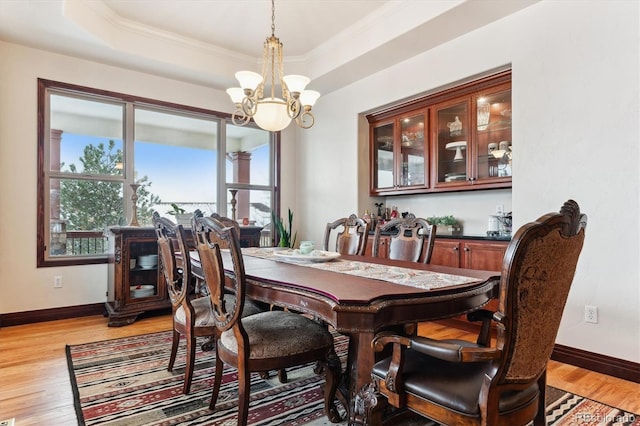 dining room featuring a tray ceiling, light hardwood / wood-style flooring, and a notable chandelier