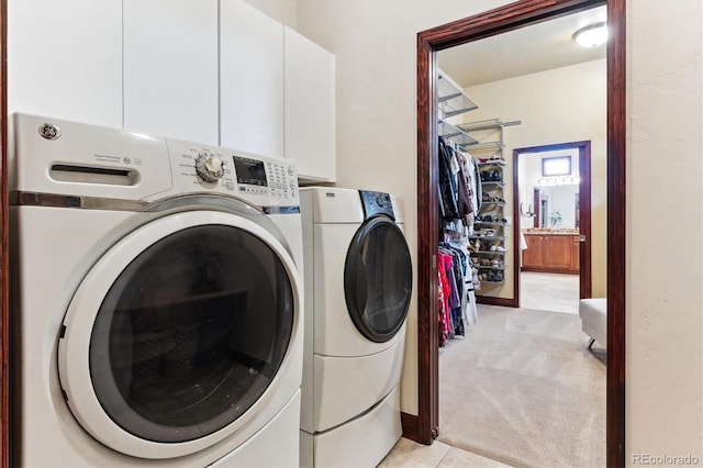 clothes washing area featuring cabinets, washing machine and clothes dryer, and light carpet