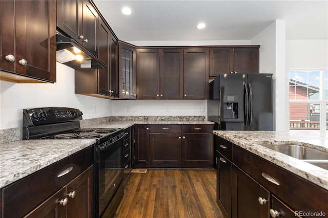 kitchen with dark wood-style flooring, dark brown cabinetry, under cabinet range hood, and black appliances